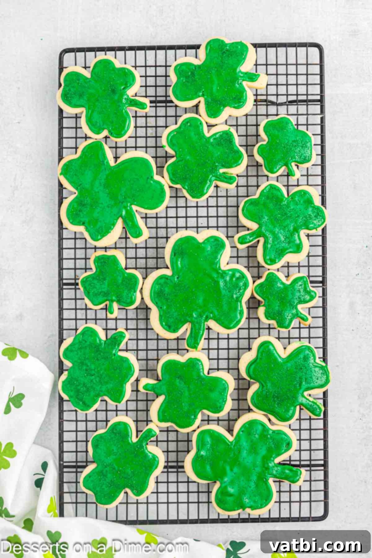 Sweet Clover Delights 14 Decorated shamrock cookies with green frosting and sprinkles, drying on a wire rack, allowing the icing to set completely.