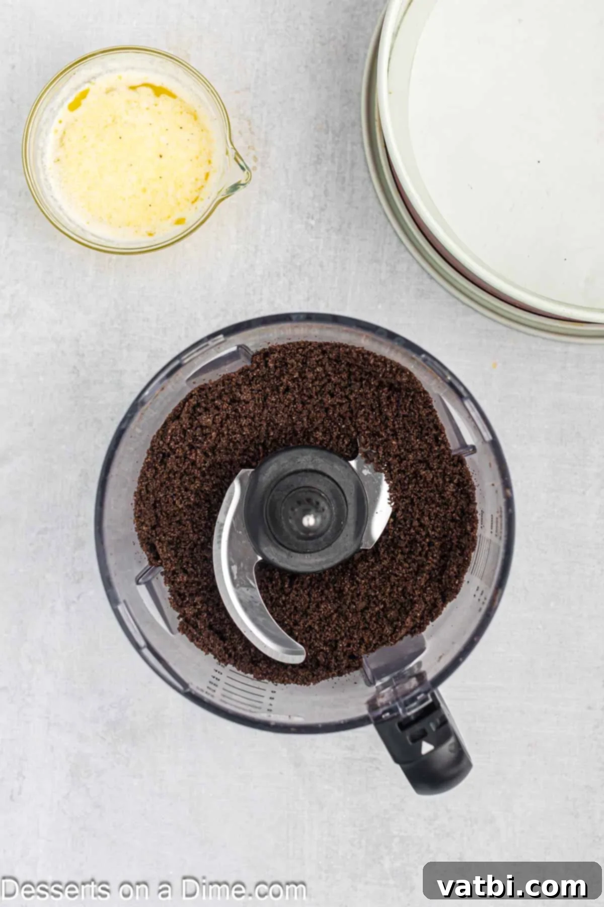 Turtle Cheesecake 4 Oreo cookies being crushed into fine crumbs in a food processor, a crucial first step for preparing the cheesecake's chocolatey crust.