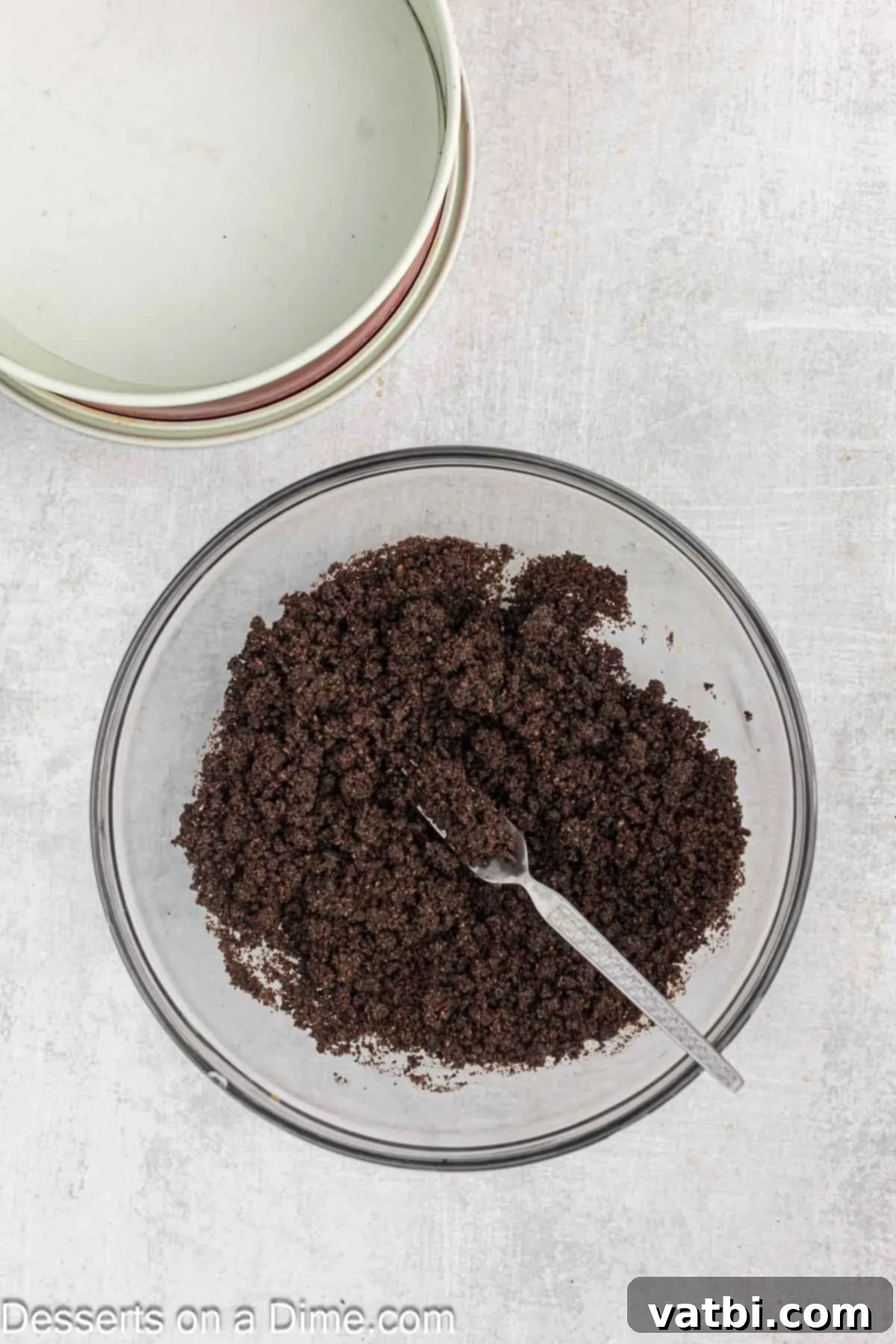 Turtle Cheesecake 5 Finely crushed Oreo cookie crumbs thoroughly mixed with melted butter in a medium-sized bowl, creating a moist, sandy texture that will form the cheesecake base.