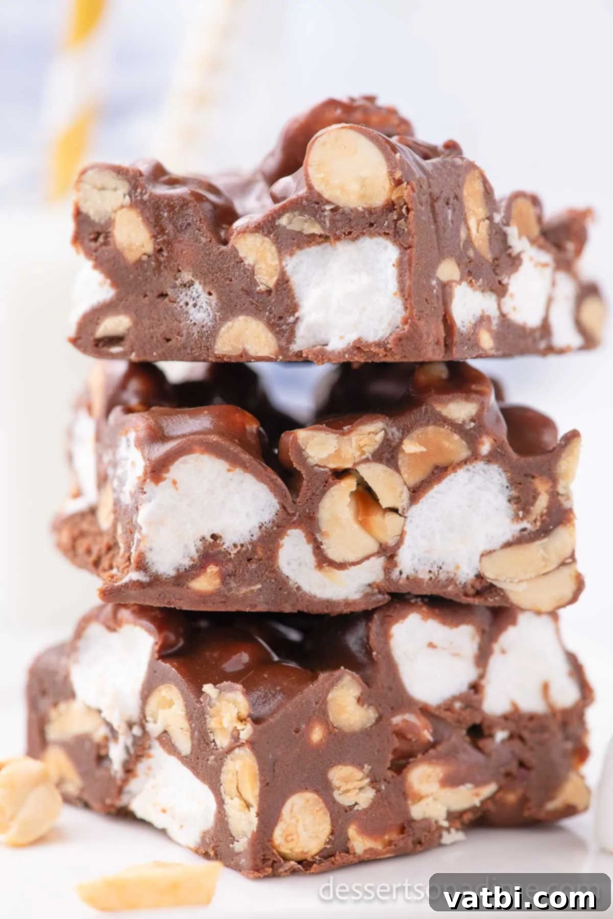 Decadent Rocky Road 2 Freshly cut squares of homemade Rocky Road Candy, rich with chocolate, fluffy marshmallows, and crunchy peanuts, stacked invitingly on a white surface.