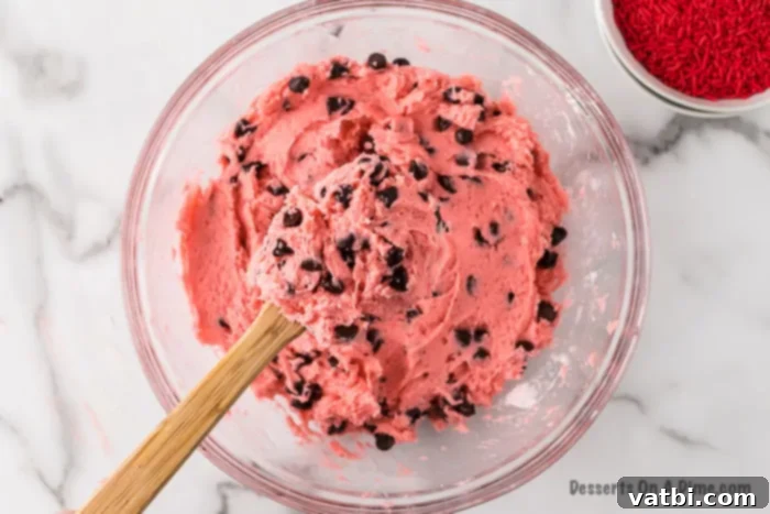 Chocolate Chip Strawberry Delights 2 Mixing bowl with vibrant pink strawberry cookie batter and semi-sweet chocolate chips folded in, ready for scooping.
