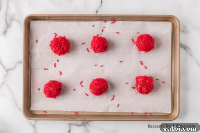 Chocolate Chip Strawberry Delights 5 Prepared cookie dough balls, coated in red sprinkles, neatly arranged on a parchment-lined baking sheet, ready for chilling.