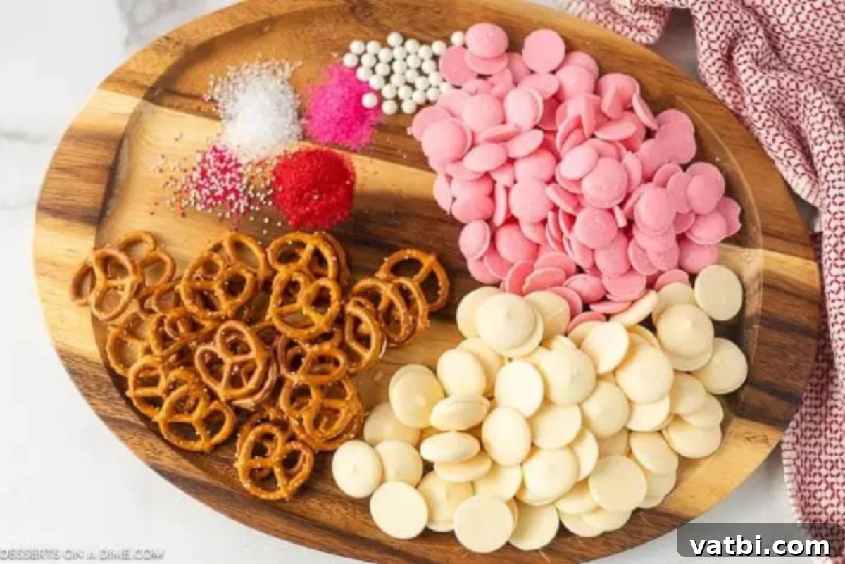 Key Ingredients for Delicious Valentine's Day Chocolate Pretzels. A flat lay image showing miniature pretzel twists, pink and white candy melts, and festive Valentine's Day sprinkles, laid out as ingredients.