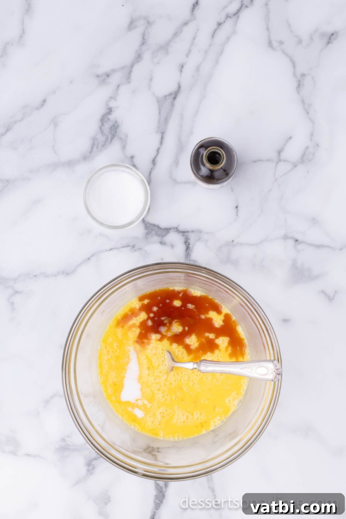 Effortless Pound Cake Perfection 4 Separate mixing bowl containing eggs, egg yolks, vanilla extract, and salt, ready to be combined.