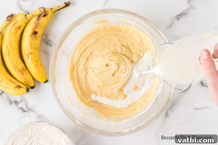 The milk and lemon juice mixture is poured into the wet butter-sugar-egg mixture in a bowl.