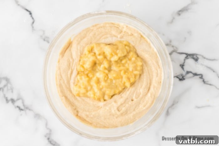 Mashed ripe bananas are gently folded into the cake batter with a spatula.