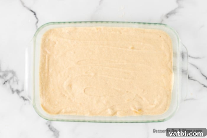 The banana cake batter is poured evenly into a 9x13 inch baking dish, ready to be baked.
