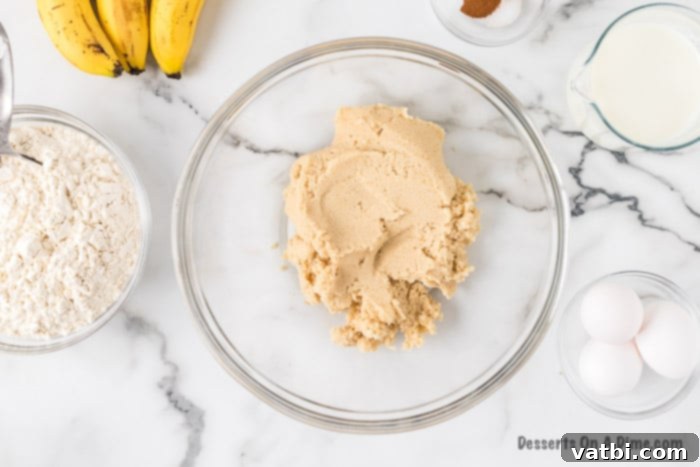 Softened butter and two types of sugar (granulated and brown) are creamed together in a mixing bowl.