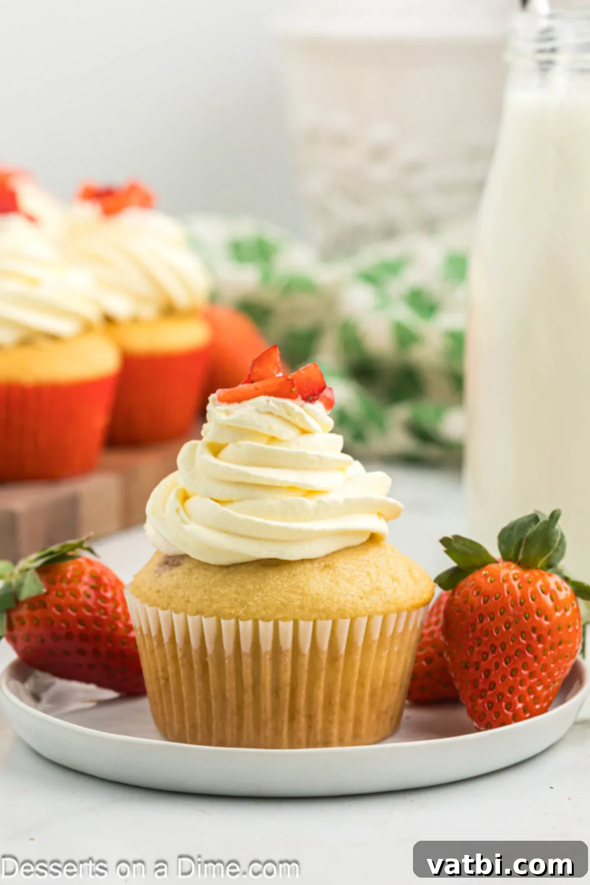 Heavenly Strawberry Shortcake Cupcakes 12 A plate of two beautiful Strawberry Shortcake Cupcakes topped with fluffy frosting and fresh strawberry slices, ready to be enjoyed.
