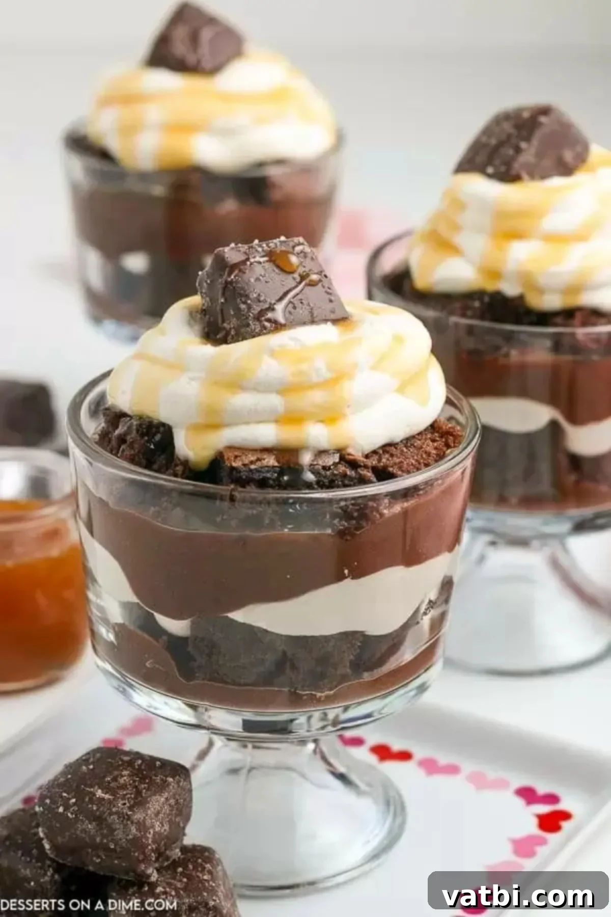 Discover the easiest and most decadent chocolate trifle recipe, featuring rich chocolate cake, creamy chocolate pudding, and luscious whipped cream. This triple chocolate layered dessert is perfect for any occasion and simple to prepare, making it a frugal and delightful treat for chocolate lovers. #chocolatetrifle #easyrecipe #layereddessert #chocolatelover #dessertideas A beautiful chocolate trifle in a clear glass bowl, generously topped with whipped cream and a luscious caramel syrup drizzle, garnished with chocolate shavings.