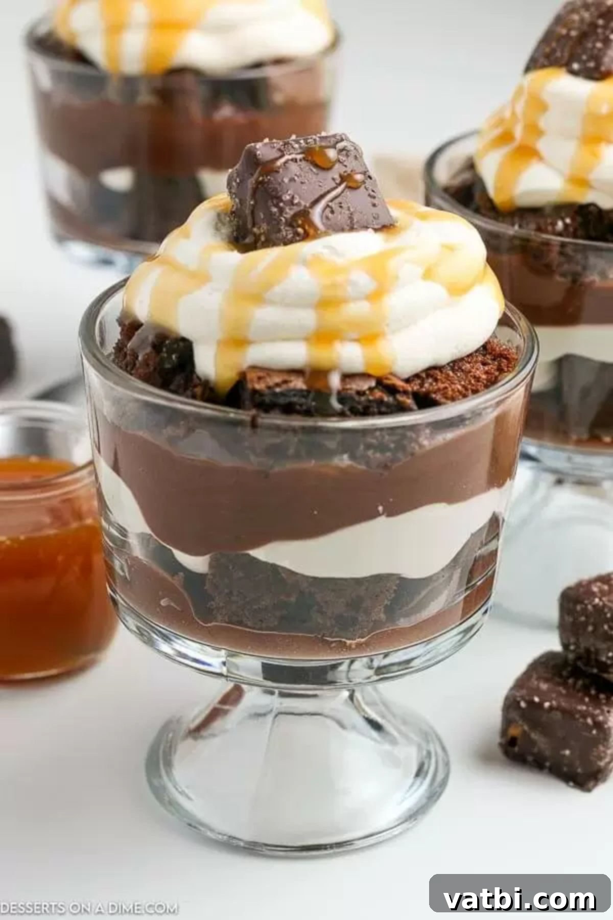 Serve this magnificent layered chocolate trifle as a decadent dessert. Its rich flavors and appealing presentation make it perfect for any occasion, promising a delightful experience for all chocolate lovers. #chocolatetrifle #dessertrecipe #easy A vibrant and fully assembled chocolate trifle, beautifully layered and garnished with whipped cream, caramel, and chocolate candy pieces, ready to be served.