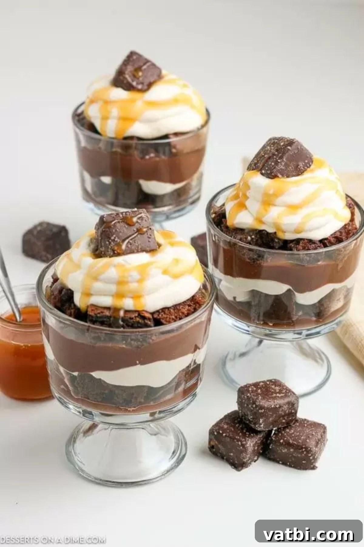 Customize your chocolate trifle with various cake and pudding flavors or make individual servings. This easy recipe allows for endless creativity to make the best layered dessert. #triflevariations #dessertideas #chocolate A close-up view of a chocolate trifle in a glass bowl, showcasing the distinct layers of chocolate cake, pudding, and whipped cream, topped with a decorative swirl of cream and caramel.