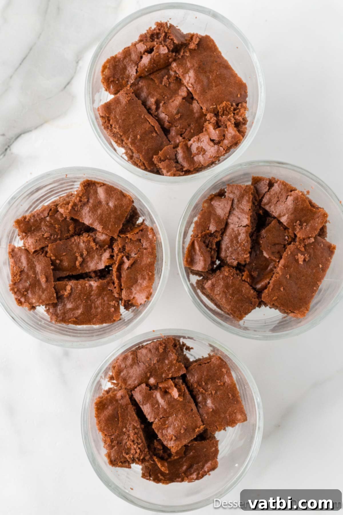 Irresistible Chocolate Trifle 4 Cubes of chocolate cake layered in individual clear dessert dishes, forming the base of the trifle.