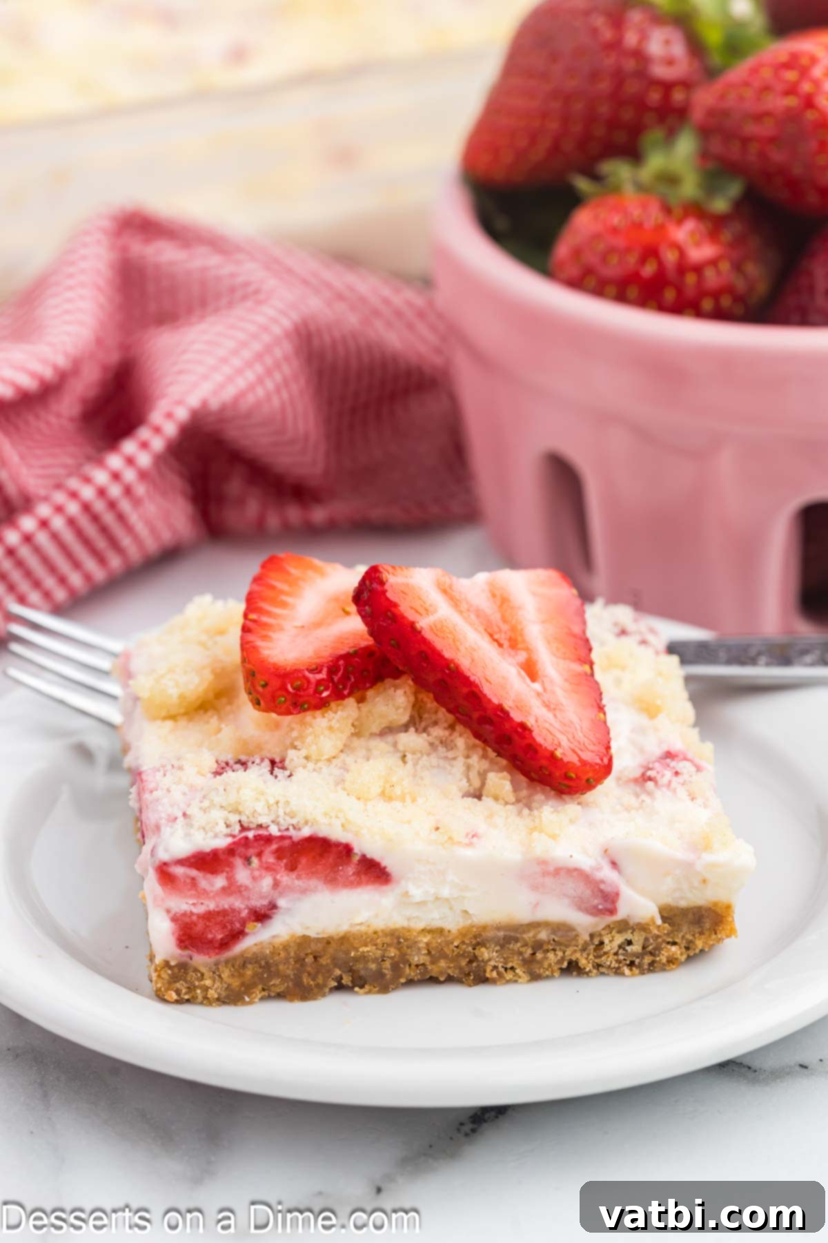 Easy Strawberry Crunch Bars 2 Beautifully sliced Strawberry Crunch Bars ready to serve on a white plate, showcasing the distinct layers of cookie crust, creamy filling, and fresh strawberries, topped with a delightful crumb.