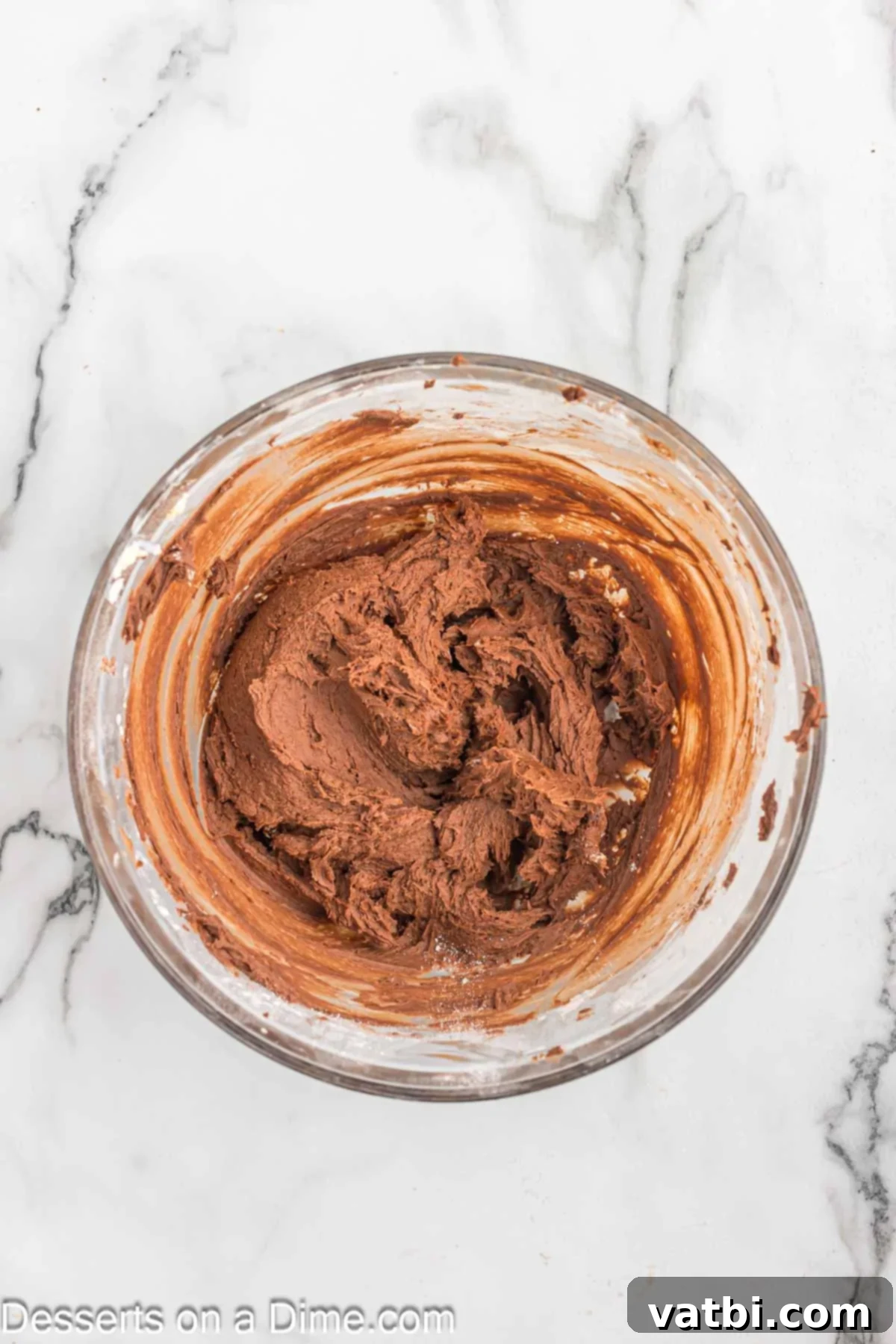 Effortless Chocolate Delight 8 Cocoa powder, heavy cream, and vanilla extract being combined with beaten butter in a bowl.