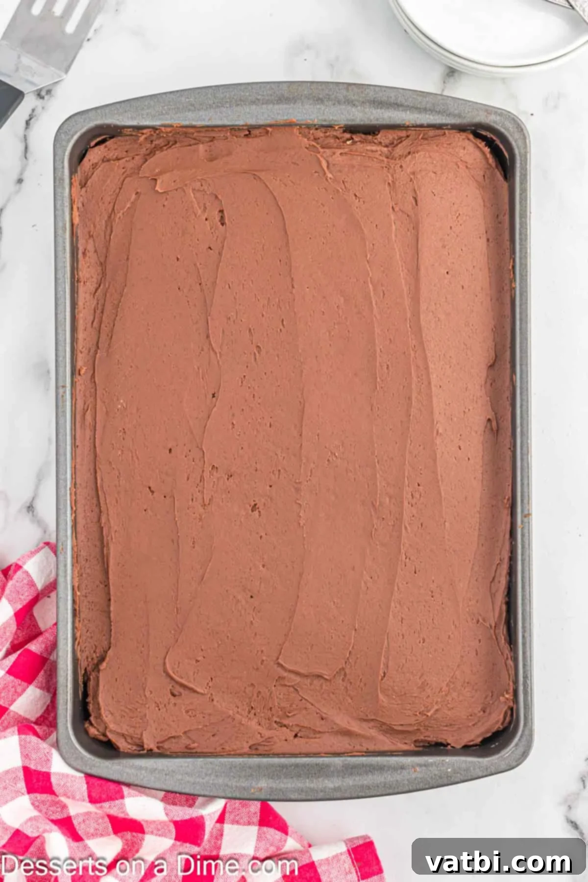 Effortless Chocolate Delight 9 Decadent chocolate buttercream frosting being spread smoothly over the cooled chocolate cake.