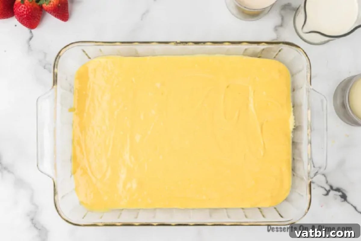 Smooth cake batter spread evenly in a 9x13 inch baking dish, ready for baking.