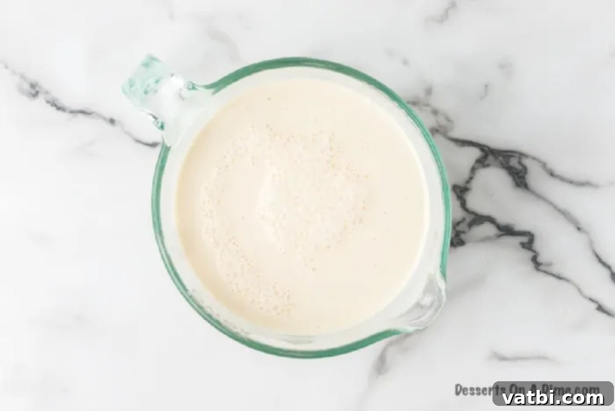 A mixing bowl filled with the combined three-milk mixture, smooth and ready to be poured.