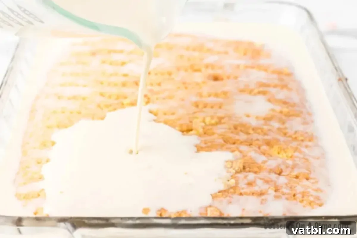 The three-milk mixture being poured over the top of a baked cake, with visible holes for absorption.
