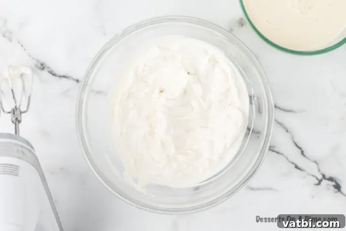 A mixing bowl with heavy whipping cream, powdered sugar, and vanilla extract, ready to be beaten for the topping.