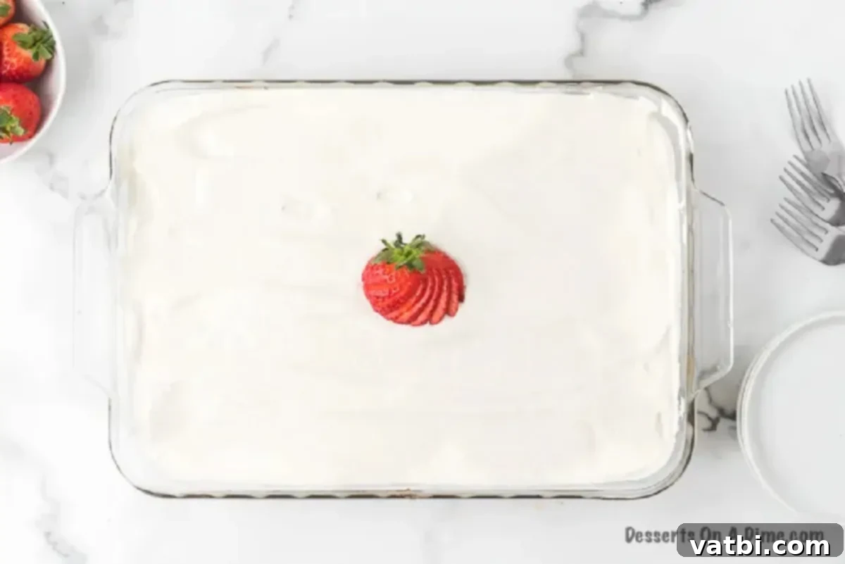 A beautifully frosted Tres Leches Cake garnished with fresh sliced strawberries and a sprinkle of cinnamon.