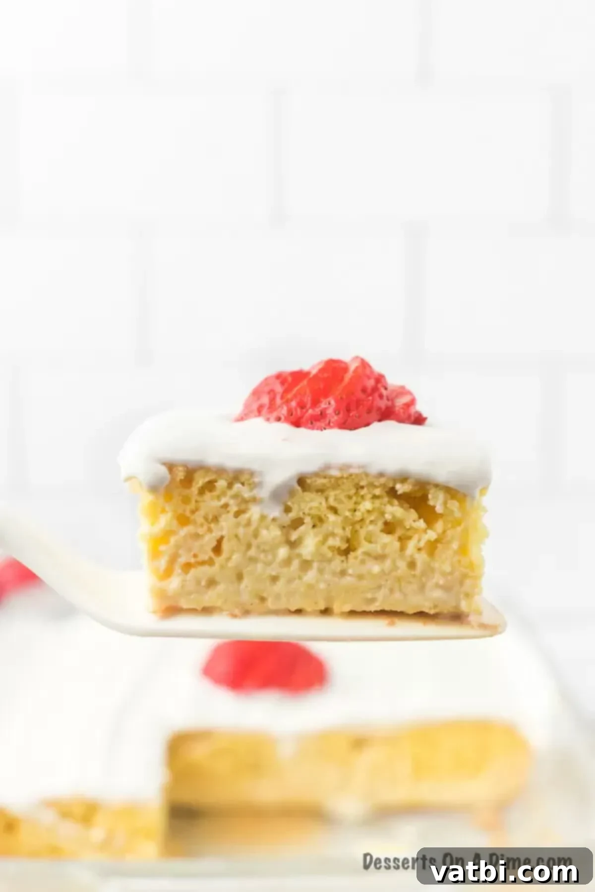 A perfect slice of Tres Leches Cake being lifted from the pan with a spatula, ready to be served.