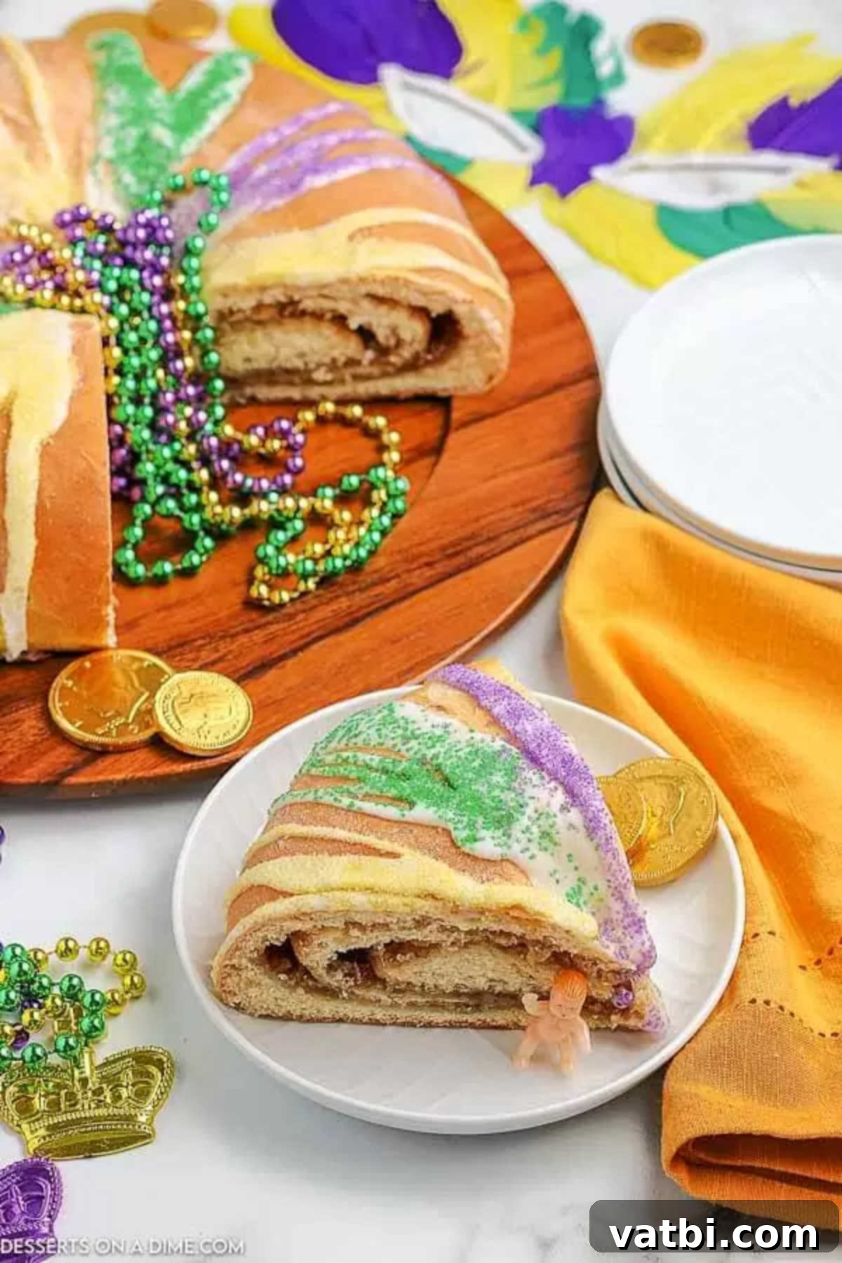 Learn how to make this Mardi Gras king cake recipe, perfect for a celebration. This cake is delicious and adorned with festive colors. A vibrant slice of Mardi Gras King Cake on a white plate, revealing the hidden baby and golden coins