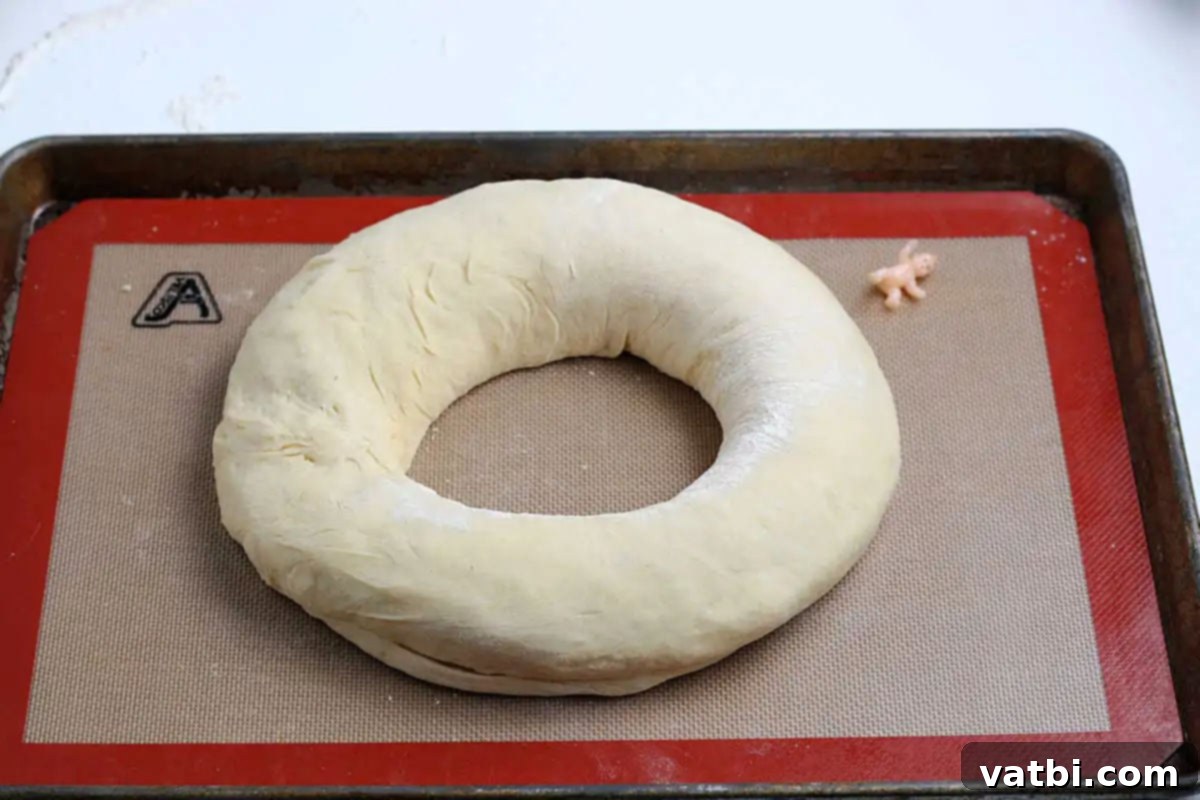 Homemade Mardi Gras King Cake 9 Dough formed into a circular shape on a baking sheet.