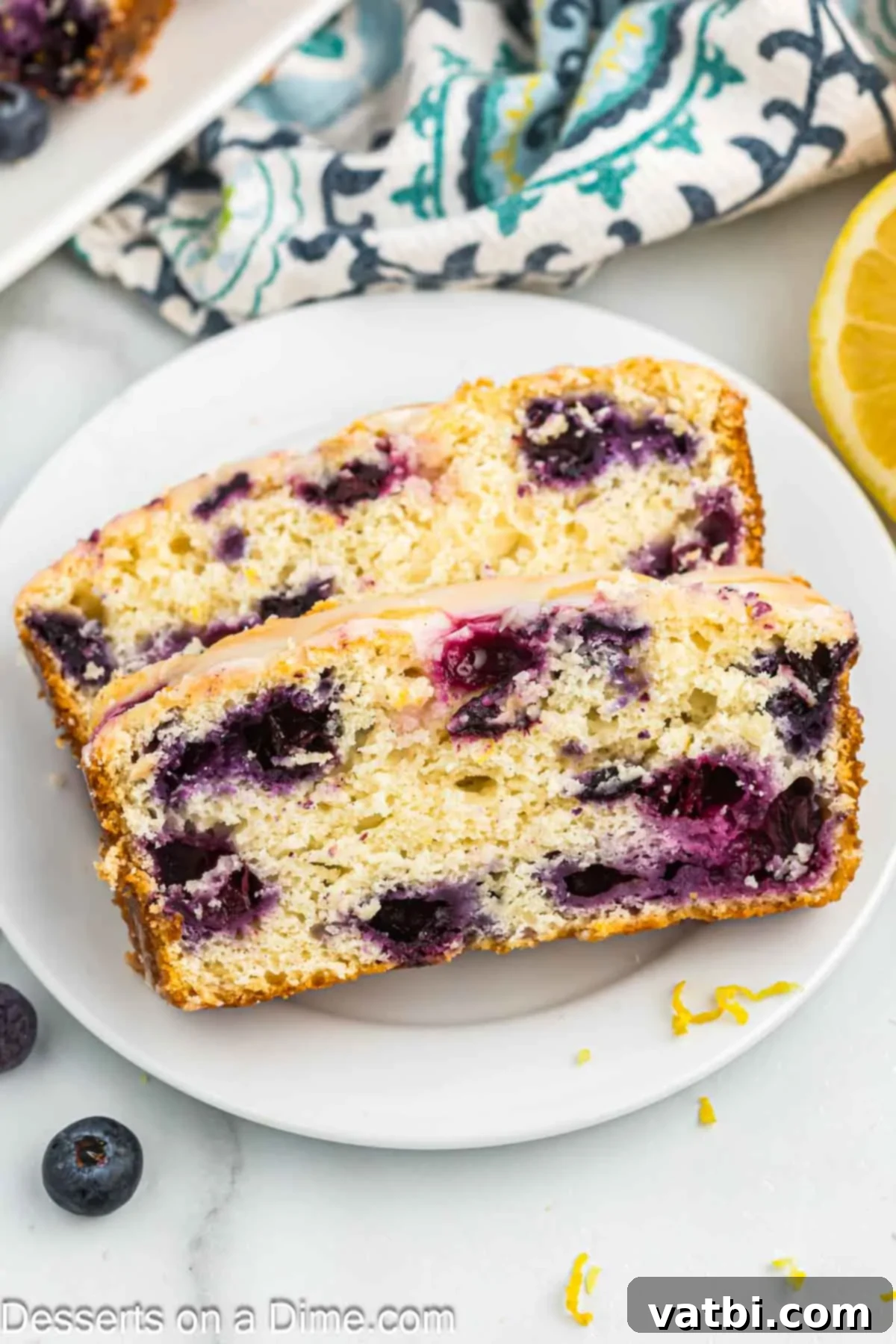 Zesty Lemon Blueberry Loaf 12 Close-up of slices of moist Lemon Blueberry Bread on a white plate, showing the berries and fluffy texture.
