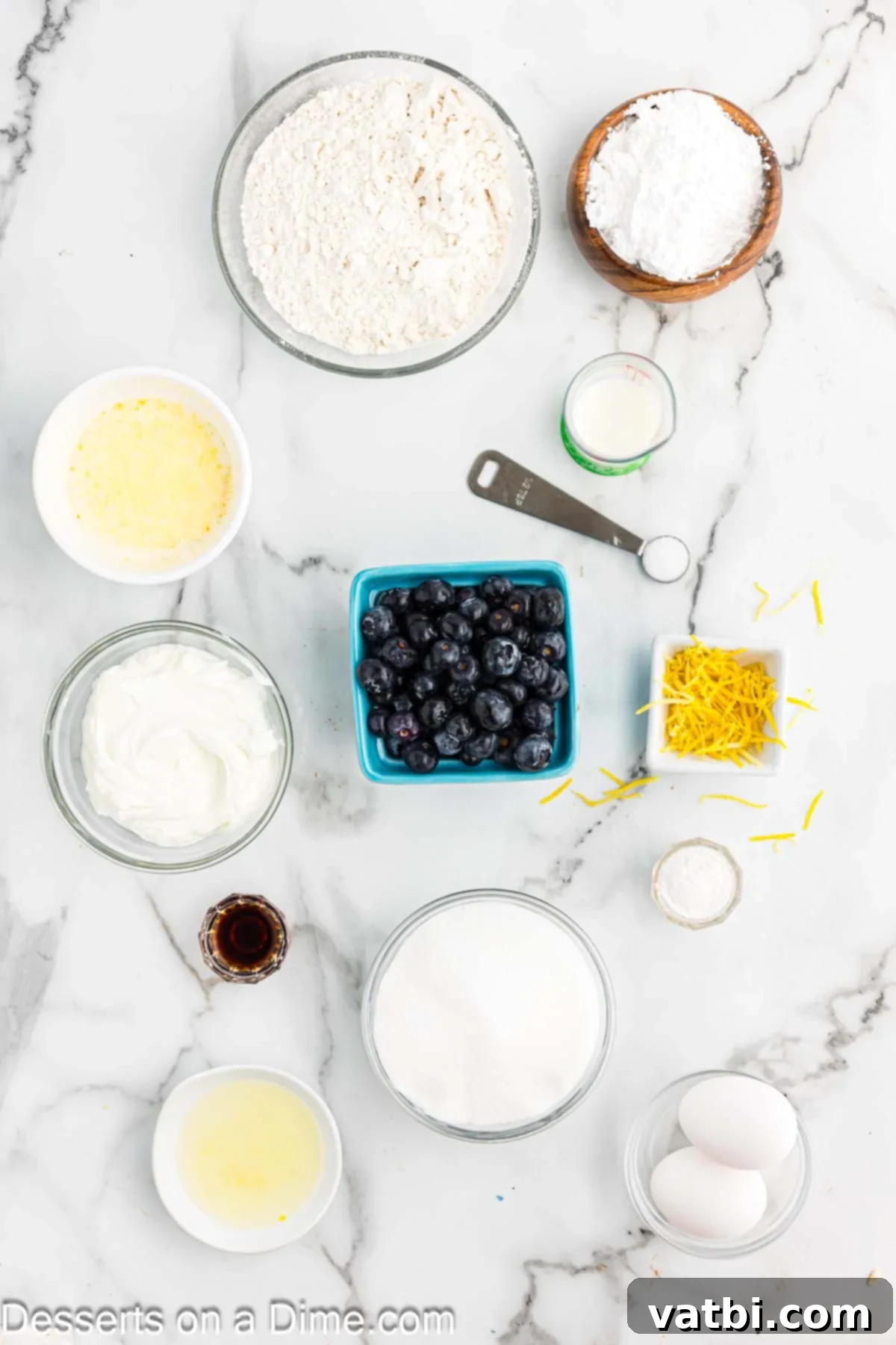 Zesty Lemon Blueberry Loaf 3 Collection of ingredients for Lemon Blueberry Bread recipe including lemon zest, Greek Yogurt, fresh lemon juice, blueberries, powdered sugar, flour, and vanilla extract.