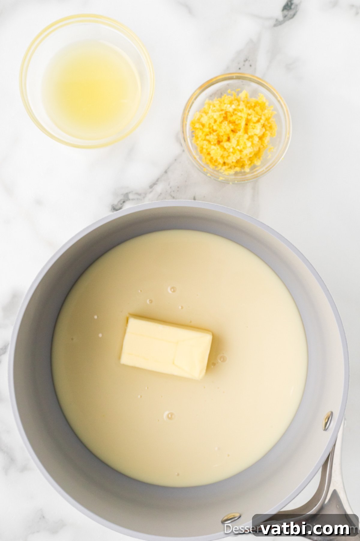 Saucepan on the stove with sweetened condensed milk, butter, lemon juice, and lemon zest beginning to melt and combine. 