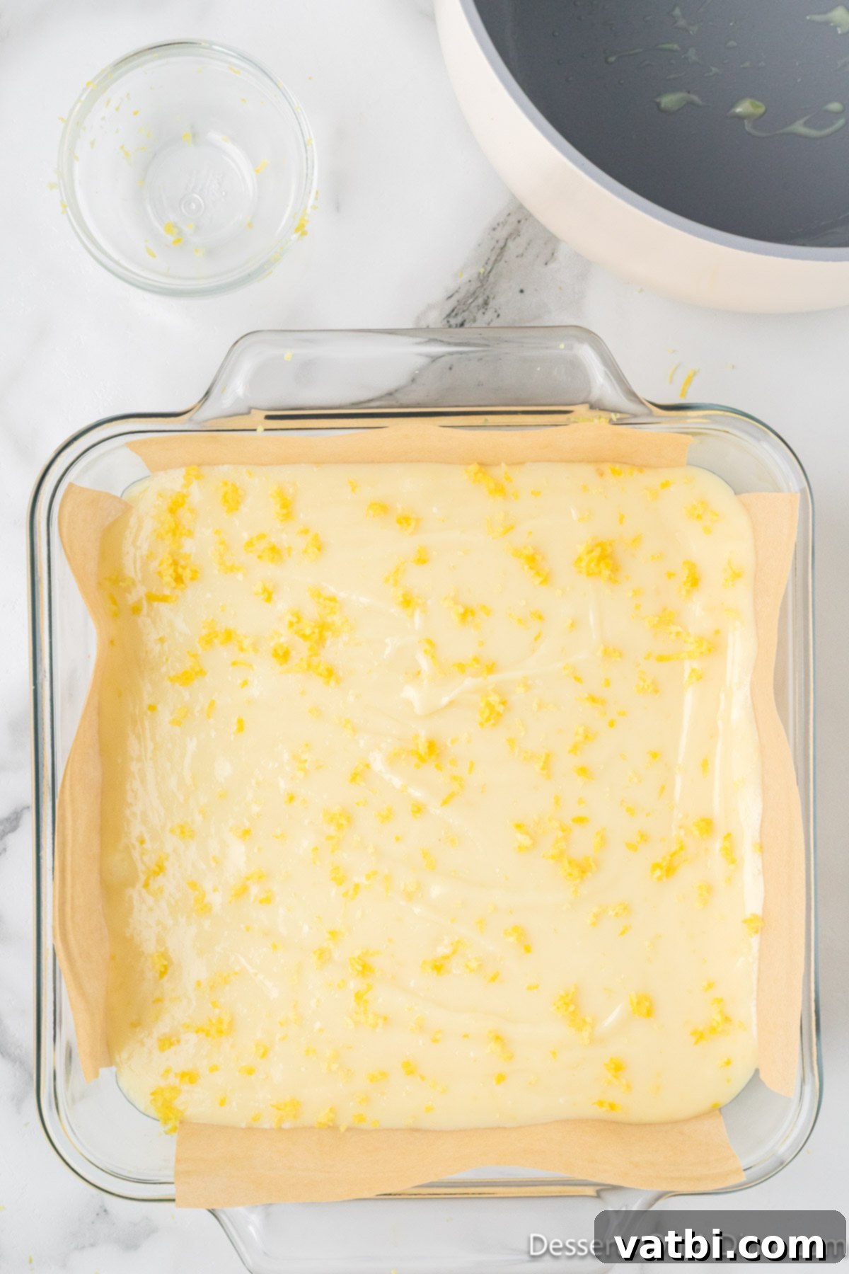 The lemon fudge mixture spread evenly into the parchment-lined pan and topped with fresh lemon zest. 