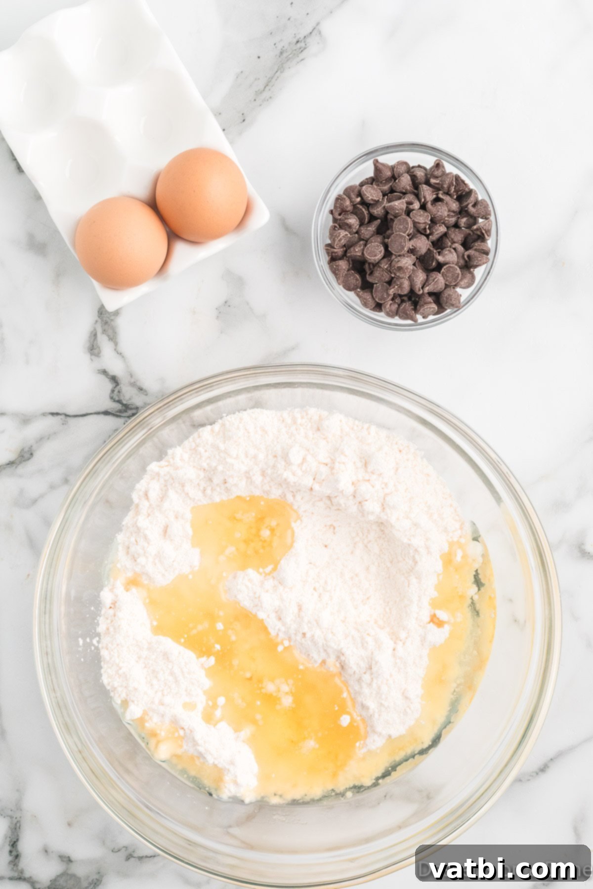 Perfect Chocolate Chip Cake Mix Cookies 4 A large mixing bowl containing yellow cake mix, vegetable oil, and two eggs, ready to be combined into a thick cookie dough.
