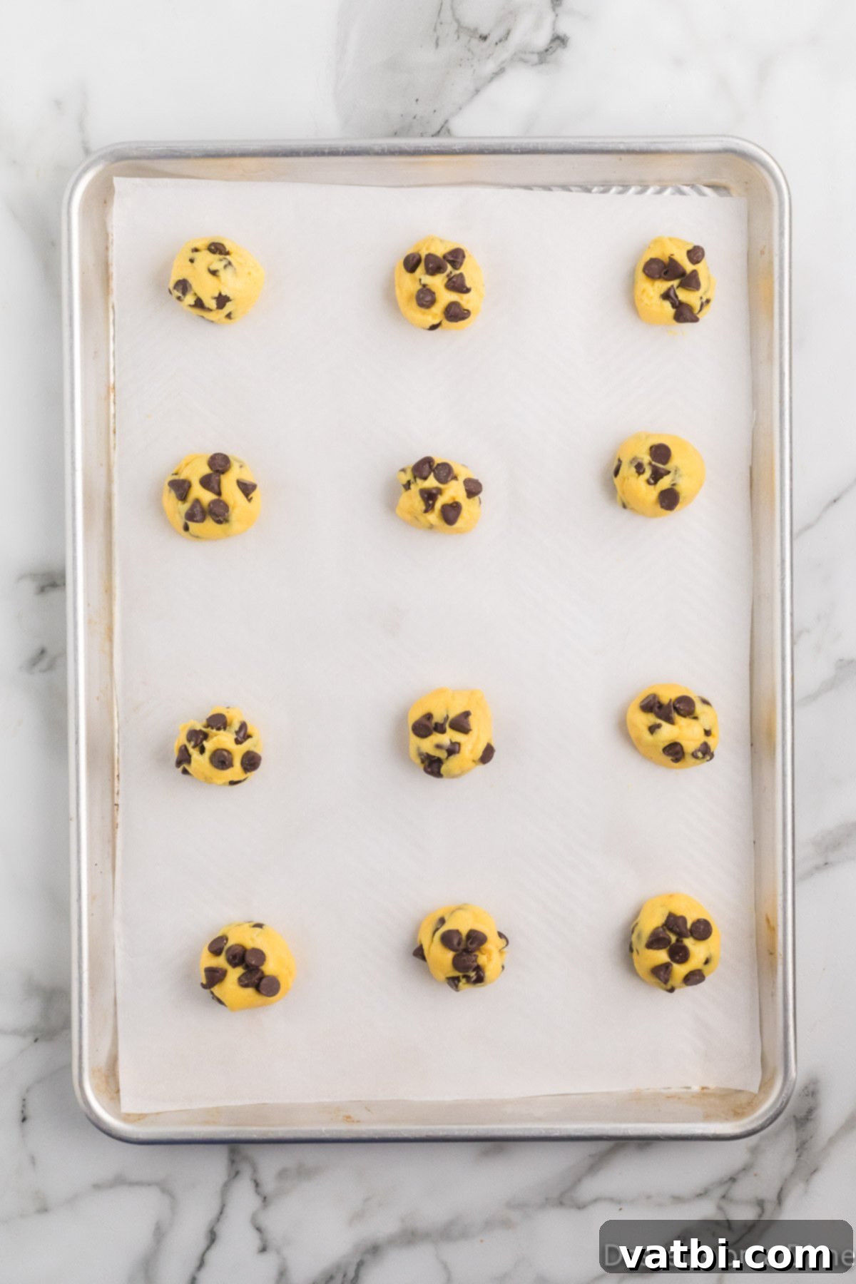 Perfect Chocolate Chip Cake Mix Cookies 6 Uniform balls of chocolate chip cake mix cookie dough, neatly scooped onto a parchment-lined baking sheet, spaced for optimal baking.