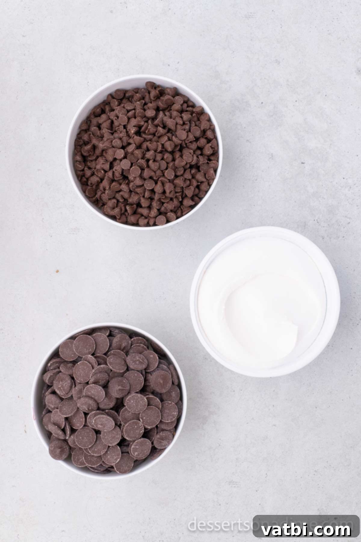 Ingredients for cool whip candy: milk chocolate chips, thawed Cool Whip, and chocolate melting wafers displayed on a counter.