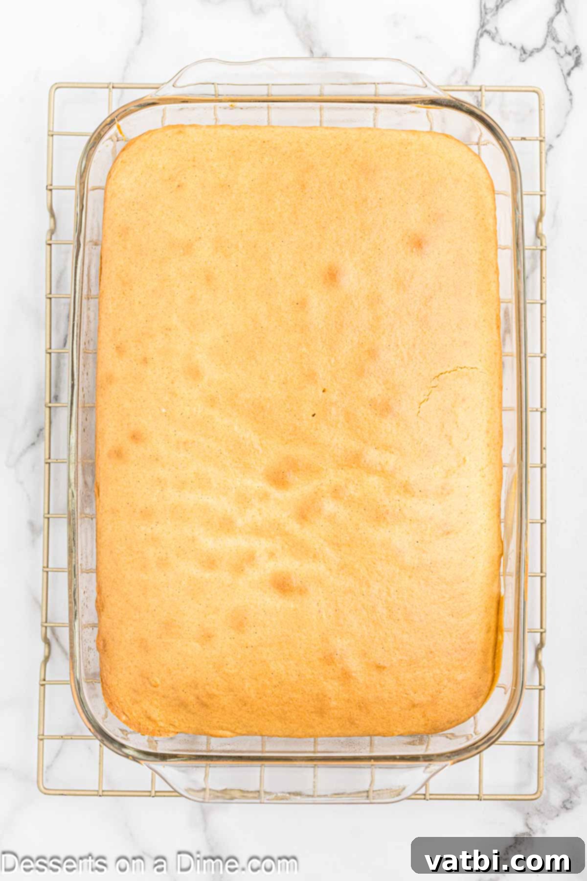 Cinnamon Whiskey Poke Cake 4 Freshly baked cake cooling in a 9x13 inch pan.