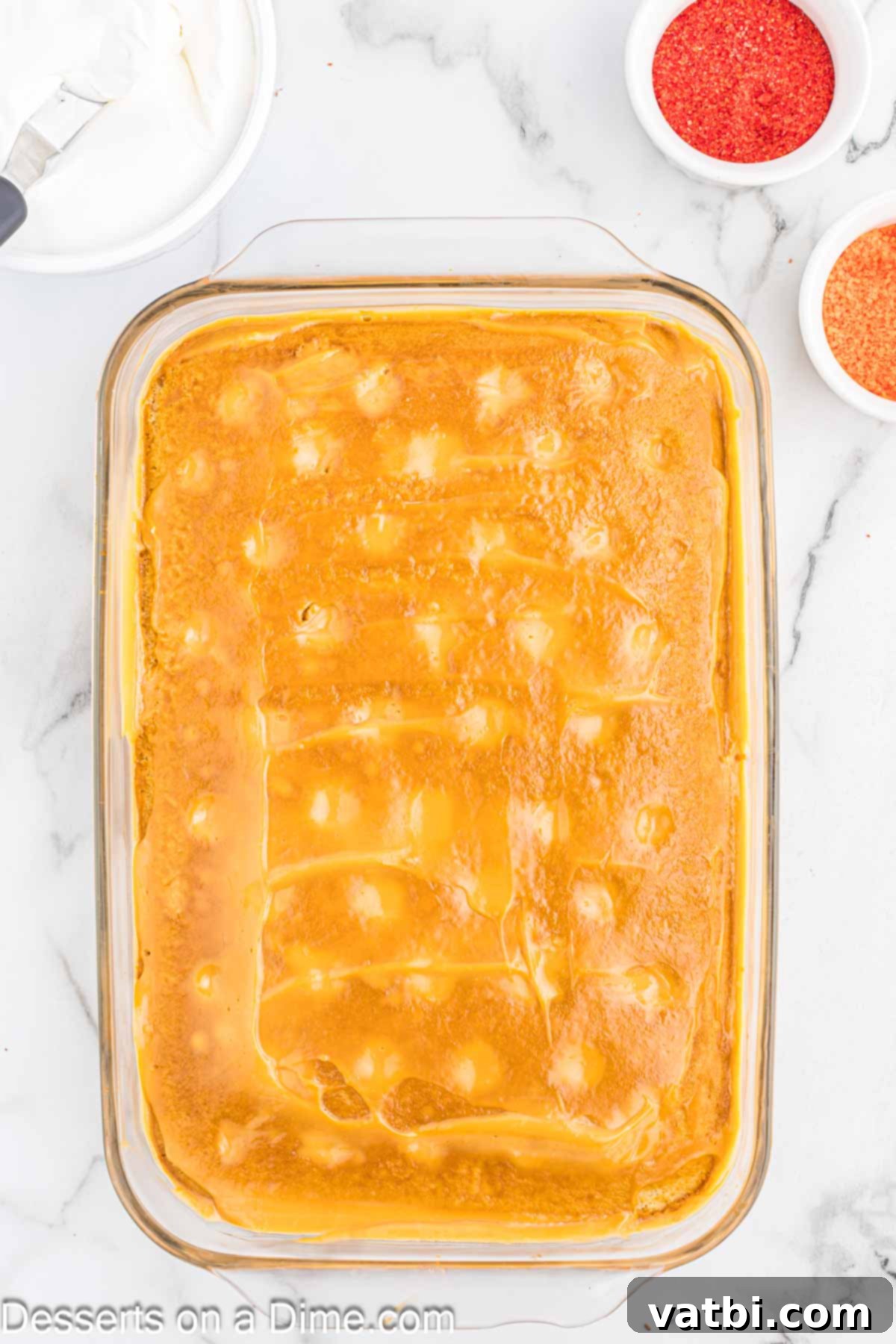 Cinnamon Whiskey Poke Cake 7 The butterscotch pudding mixture being spread evenly over the poked cake, sinking into the holes.