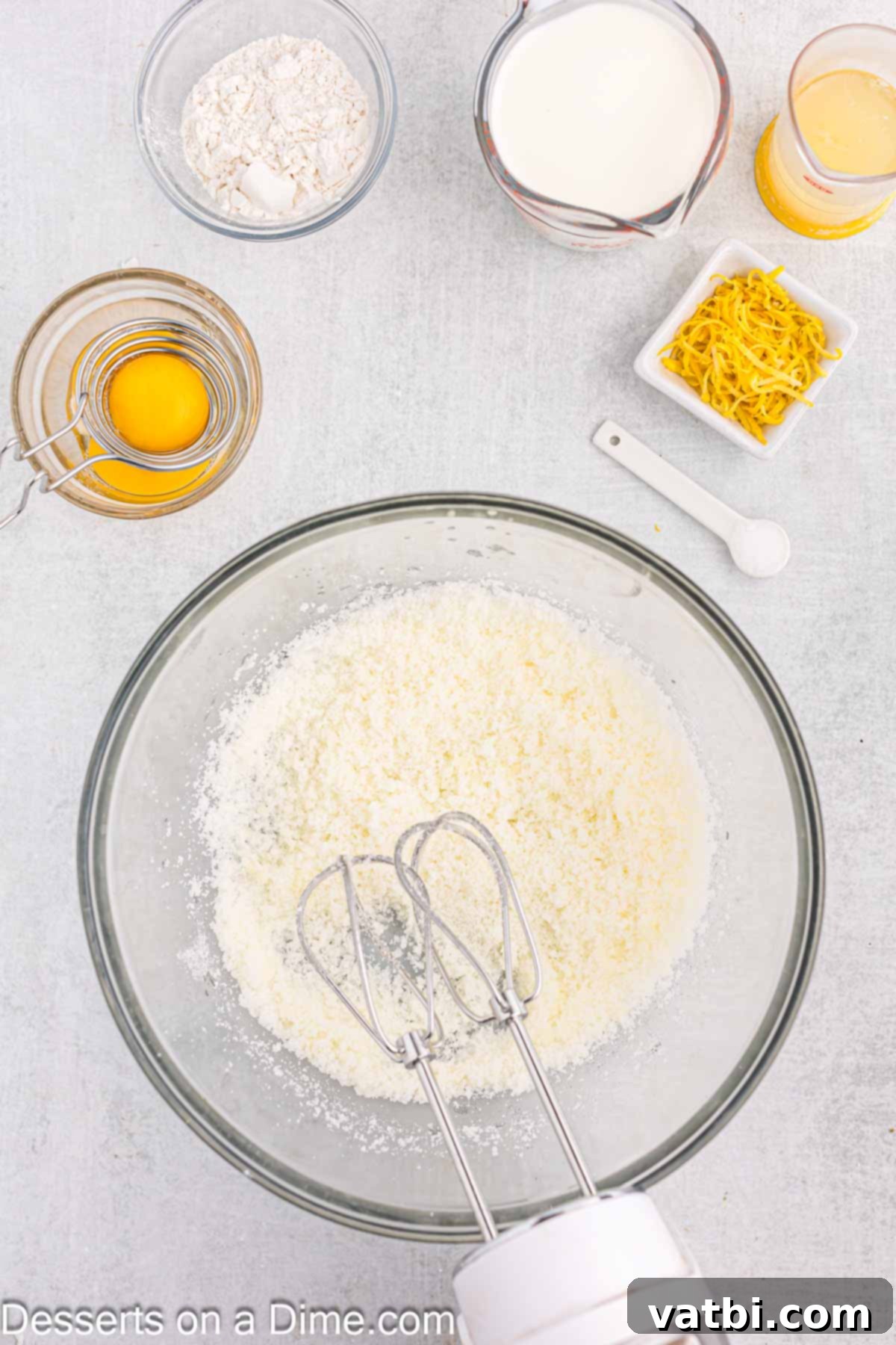 Zesty Lemon Pudding Cake 4 Close-up of butter and sugar being creamed together in a large mixing bowl with an electric mixer.
