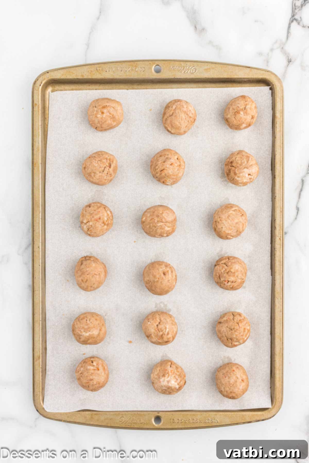 Spiced Carrot Cake Bites 7 Uniform cake balls arranged neatly on a baking sheet lined with wax paper, ready for chilling.