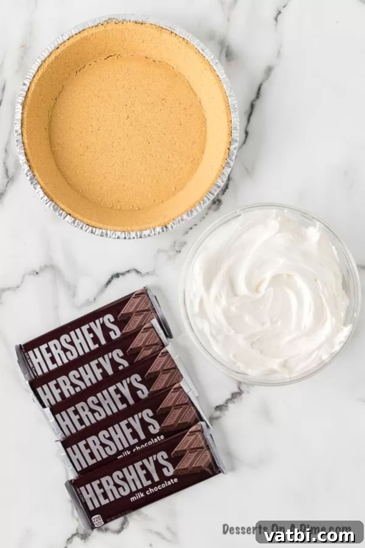 Ingredients to make No Bake Hershey Pie - a pre-made graham cracker crust, several Hershey's chocolate bars, and a tub of Cool Whip, neatly arranged.
