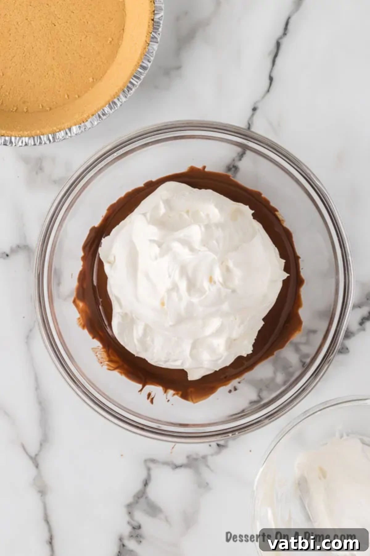 Gently combining the cool whip with the melted chocolate in a large mixing bowl, showing a swirl of white and brown.