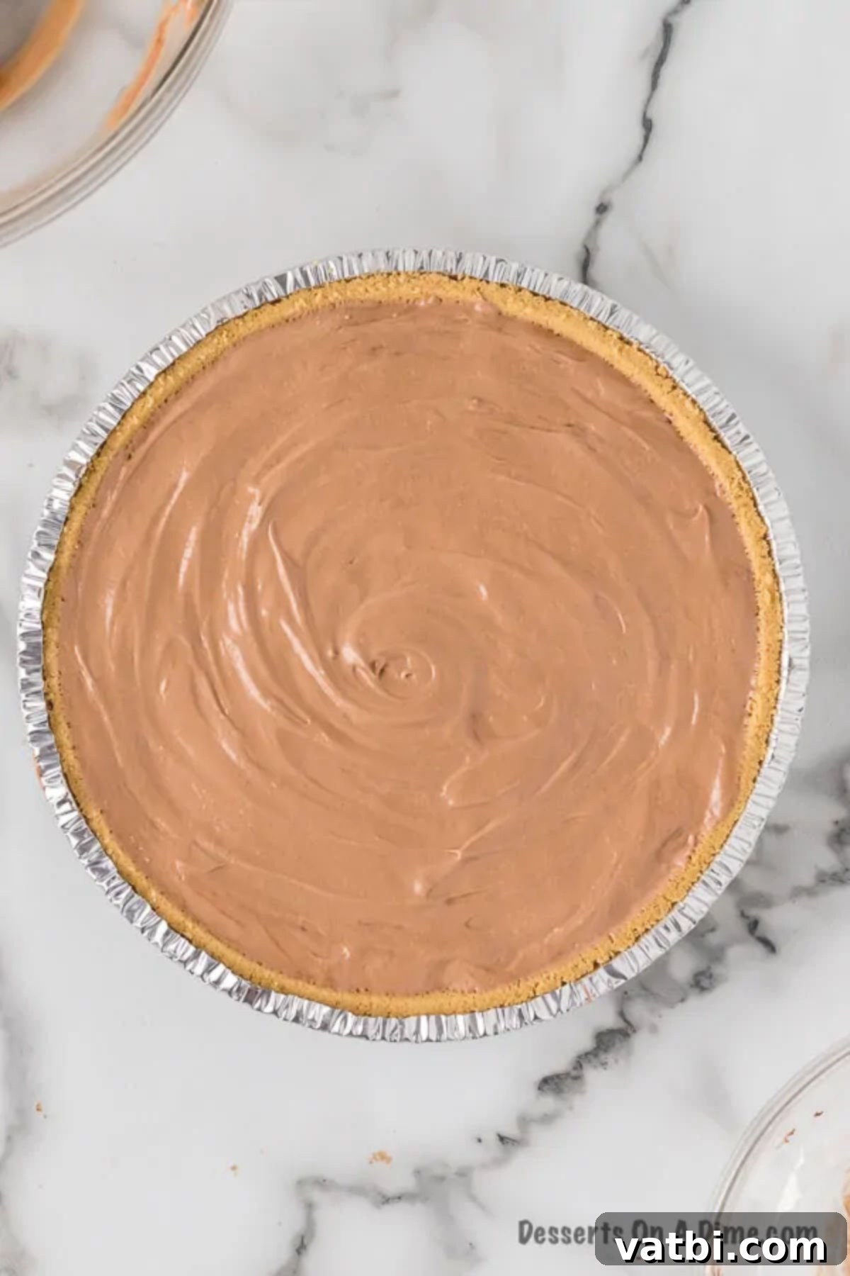 Placing the chocolate filling mixture evenly into the prepared graham cracker pie crust.