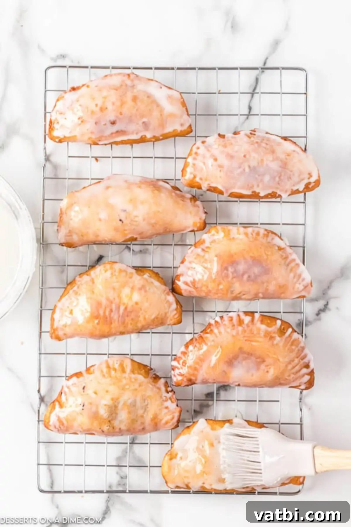 Golden Fried Apple Pockets 9 Fried pies on cooling rack with glaze added.