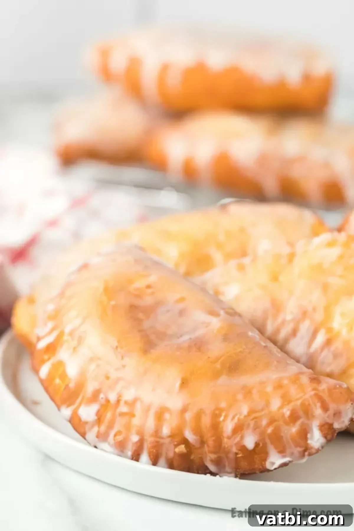 Fried apple pies recipe made with biscuit dough and a delicious apple filling come together for the best dessert. Top it off with glaze! Fried Apple Pies stacked on a plate
