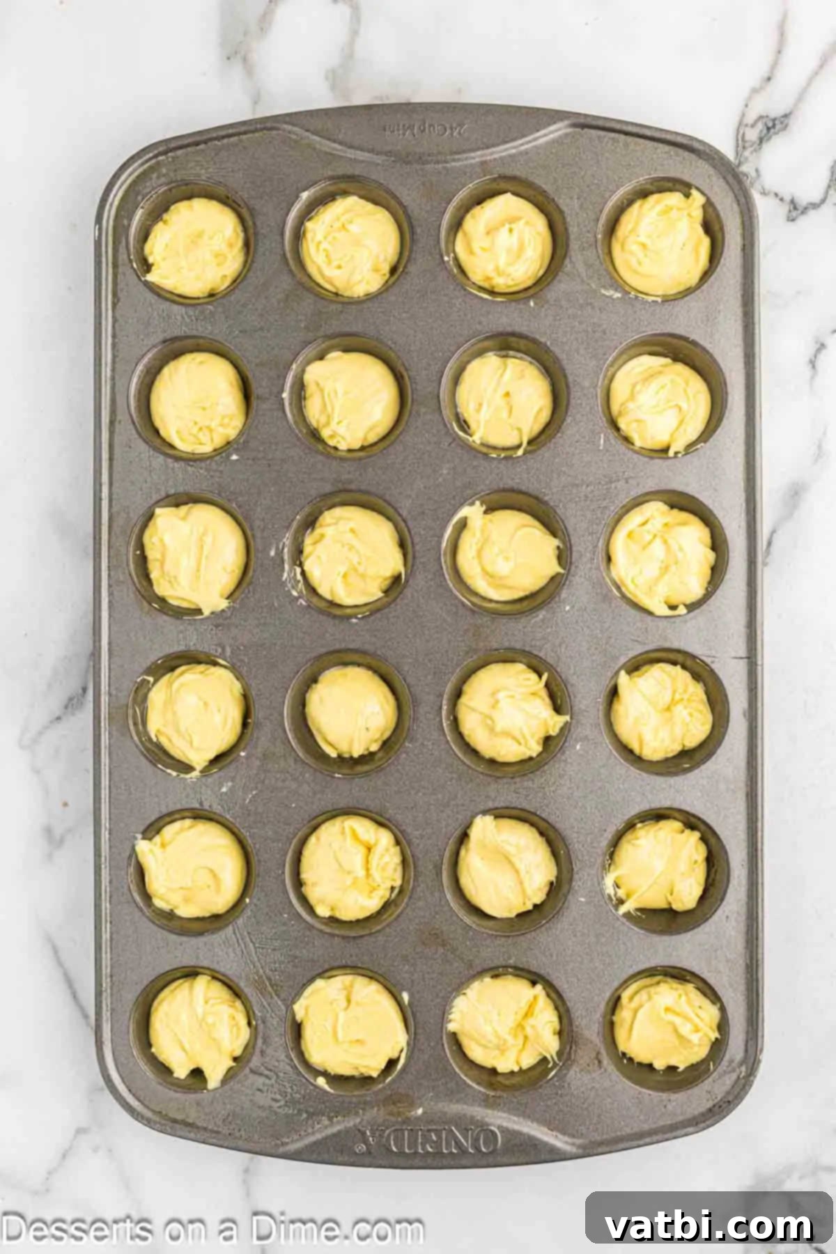 Pouring lemon blossom batter into mini muffin tins.