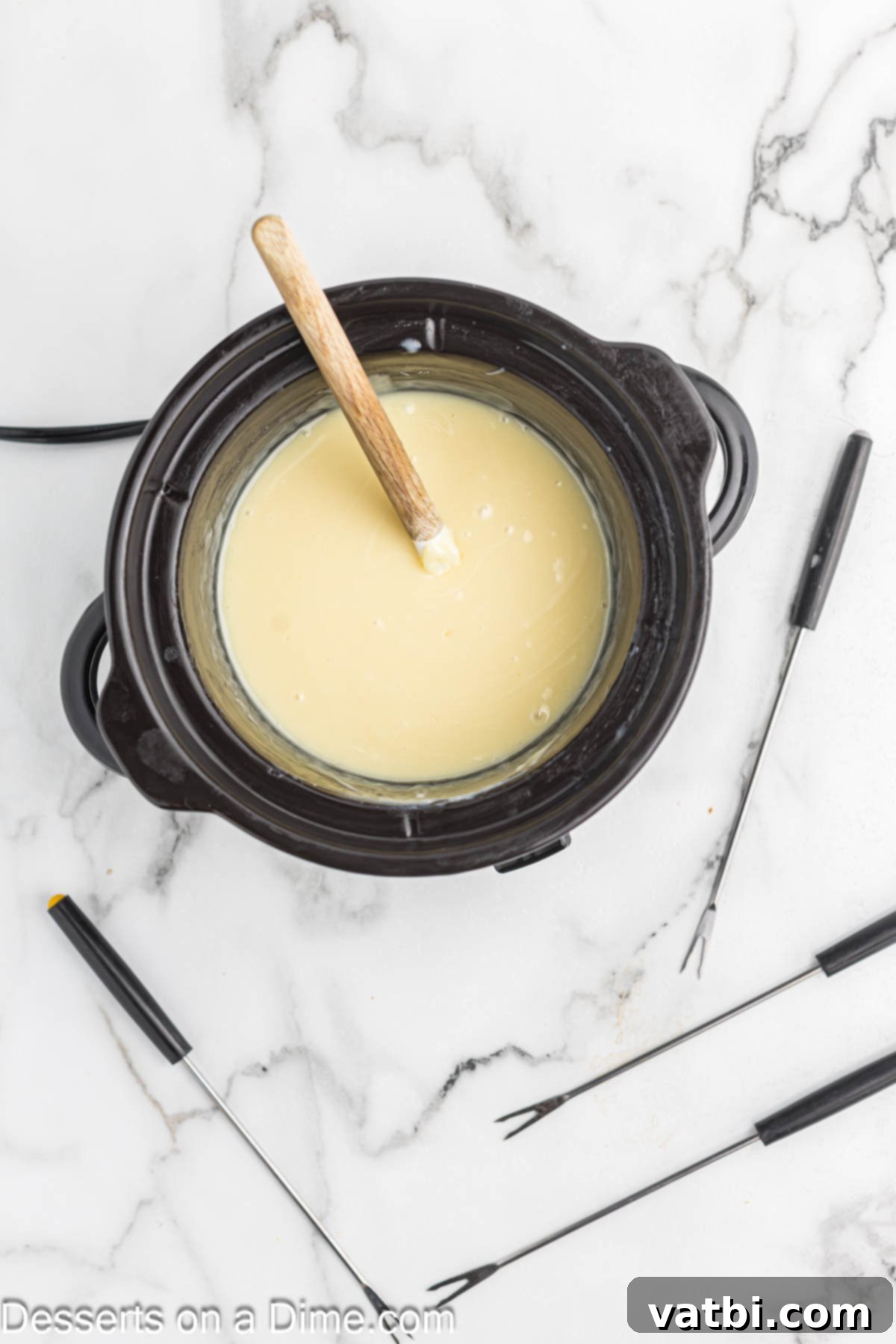 Decadent White Chocolate Fondue 4 Melted white chocolate mixture in a crock pot, ready for fondue.