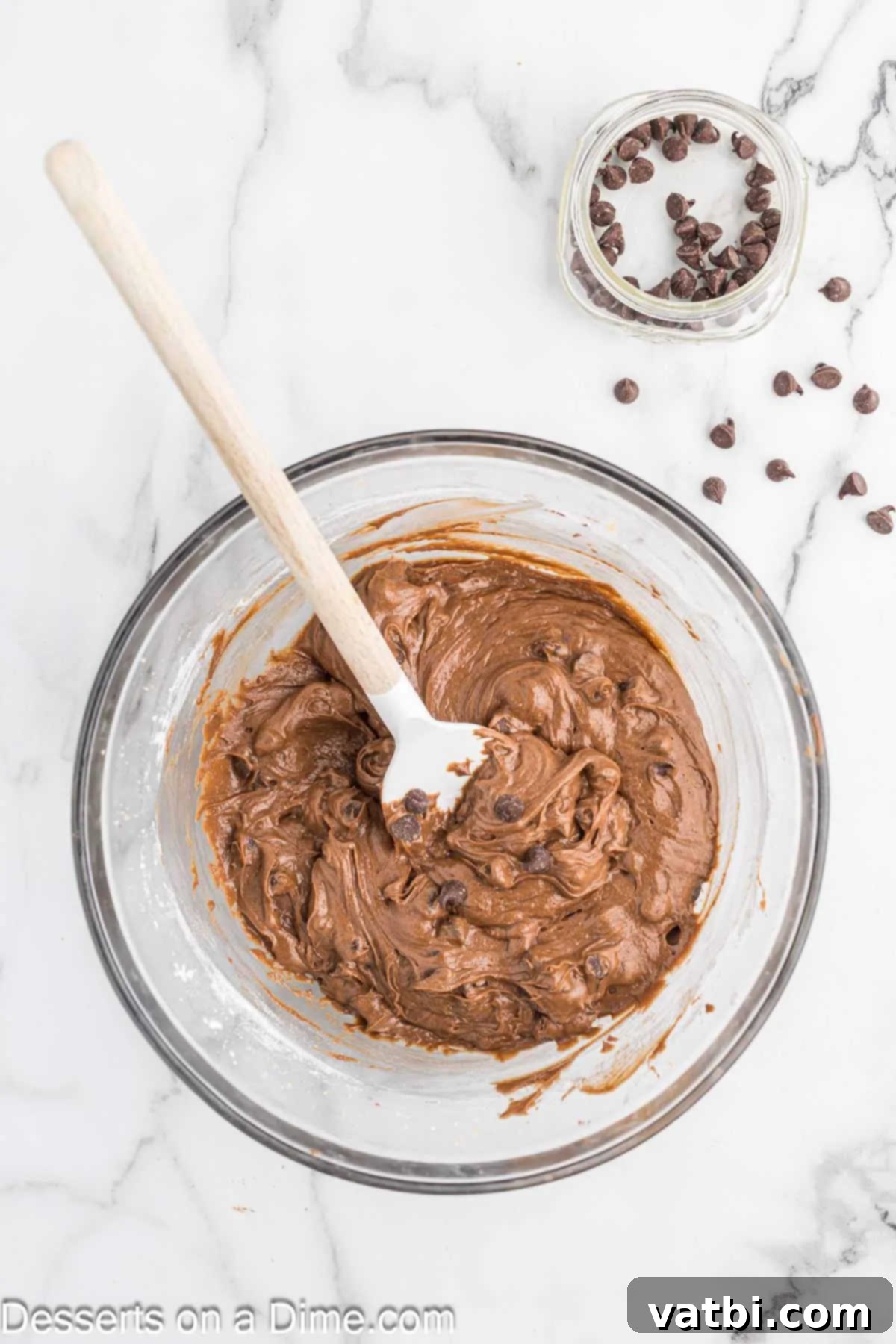 Decadent Nutella Brownies 7 Semi-sweet chocolate chips being gently folded into the luscious Nutella brownie batter using a spatula, ensuring even distribution without overmixing.