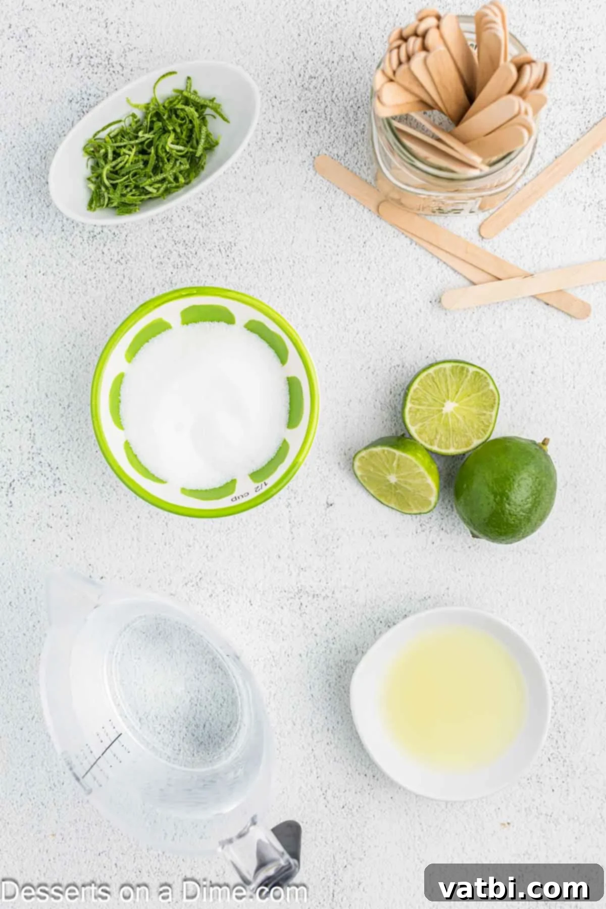 Enjoy light and refreshing lime popsicles when you make this recipe. It is the perfect summer time treat and the entire family will enjoy. Close-up of fresh limes, sugar, and a bowl of lime juice, showcasing the simple ingredients for homemade lime popsicles.