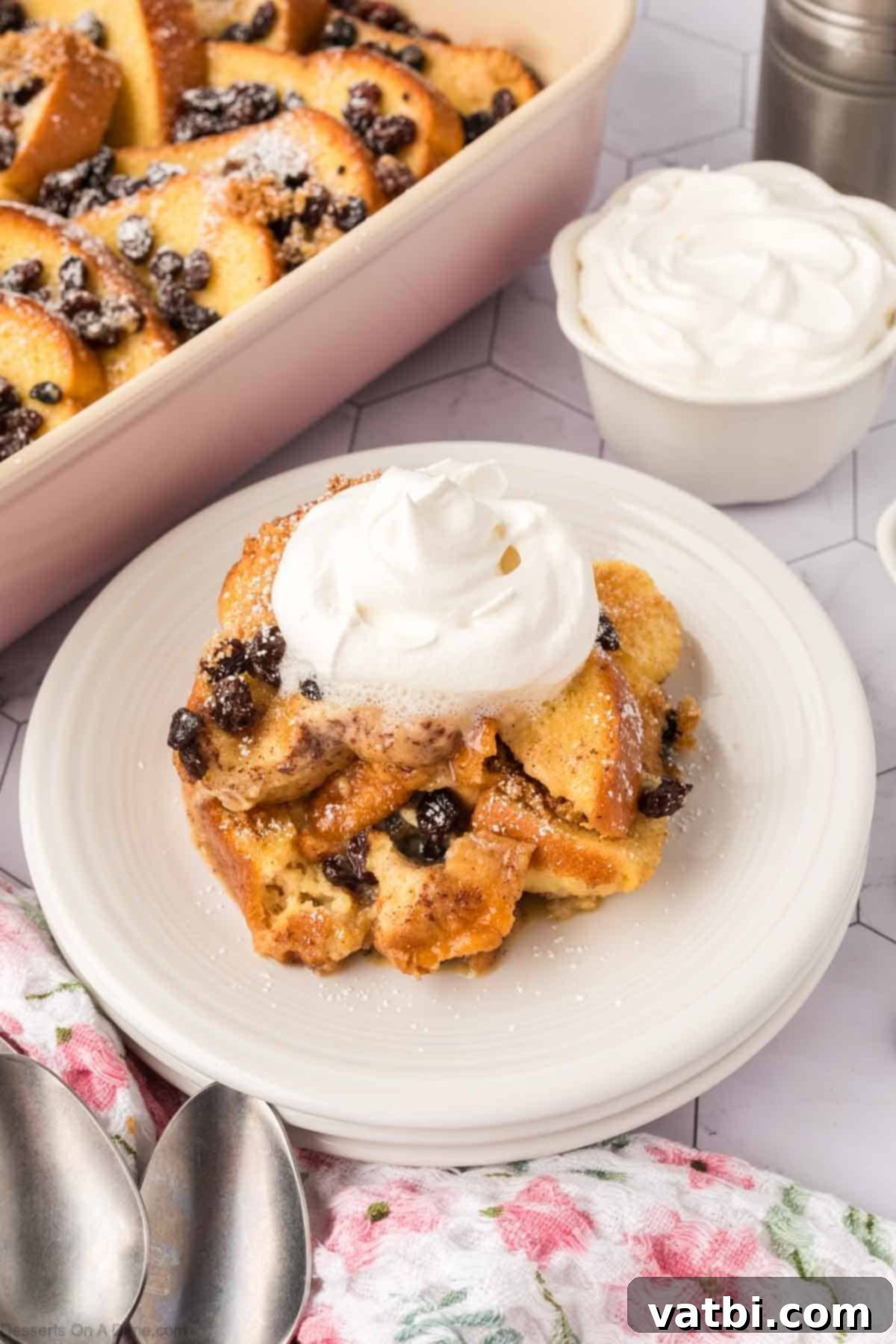 A close-up of a serving of bread pudding on a plate, garnished with whipped cream and a hint of mint, showing its rich, comforting texture.