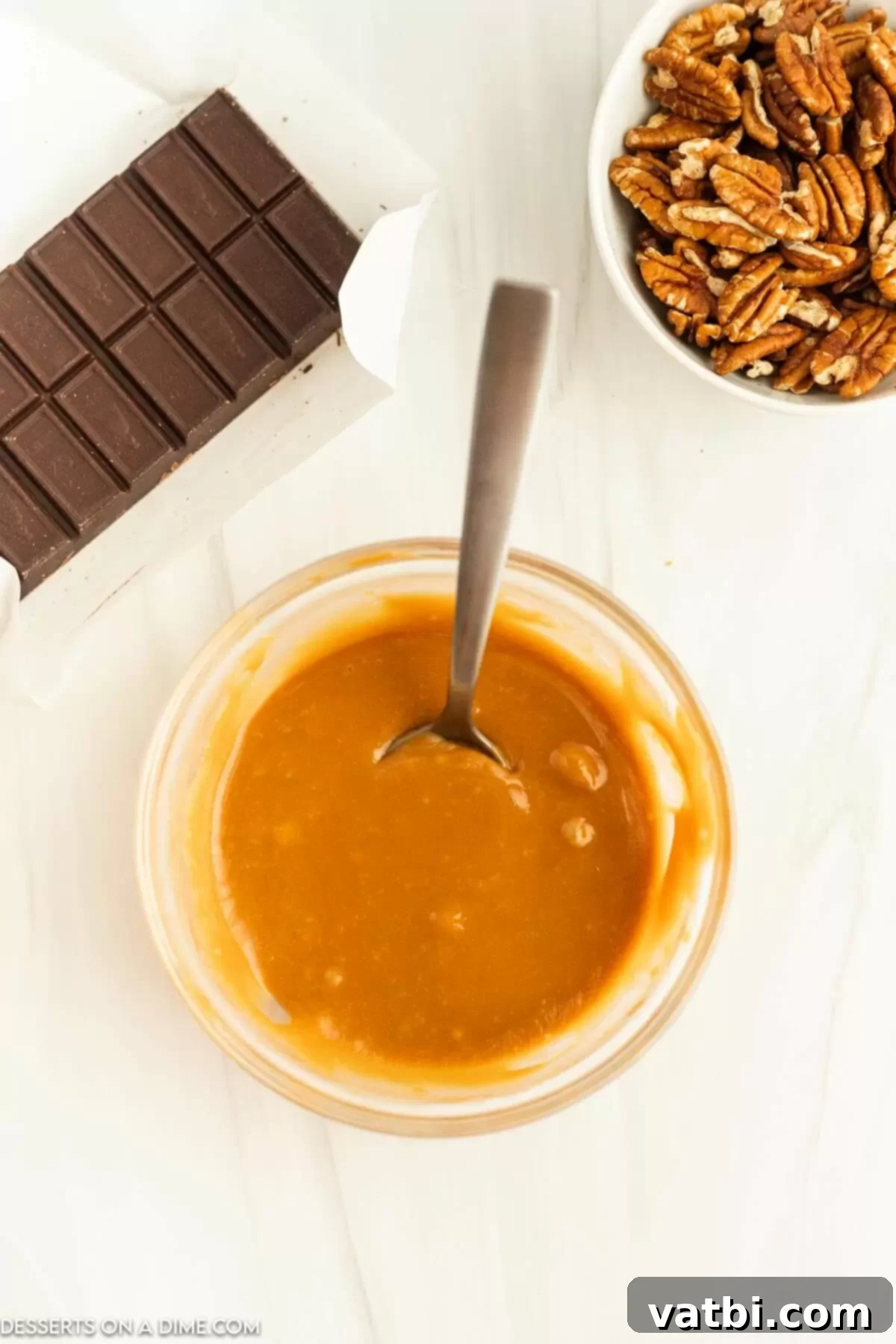 A bowl of smooth, melted caramel sauce, ready to be poured over pecan clusters.
